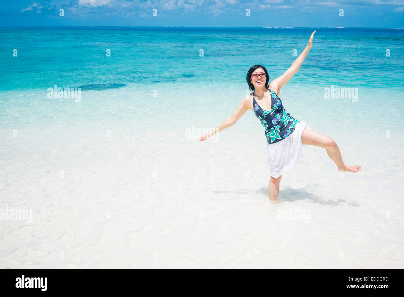 Malediven, Ari Atoll, junge Frau, die im Wasser auf einem Bein stehend Stockfoto