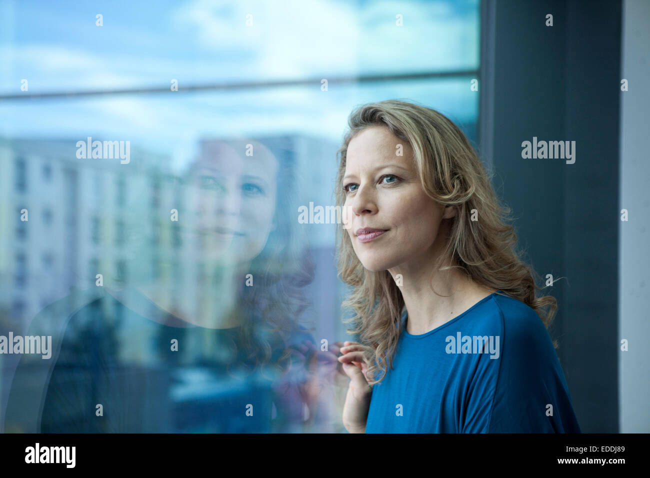 Porträt von Reife Frau Blick durch Fenster in ihrer Wohnung Stockfoto
