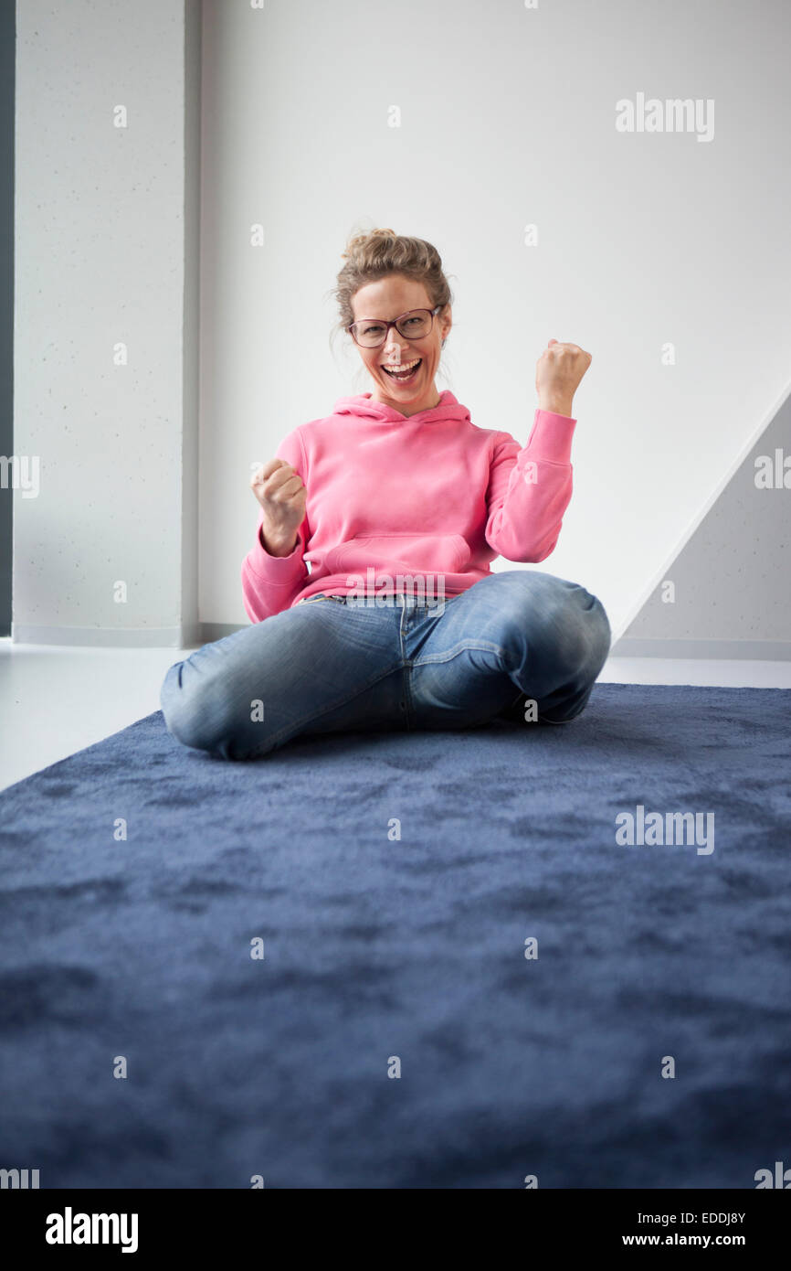 Reife Frau sitzen auf dem Boden ihrer Wohnung begeistert Stockfoto