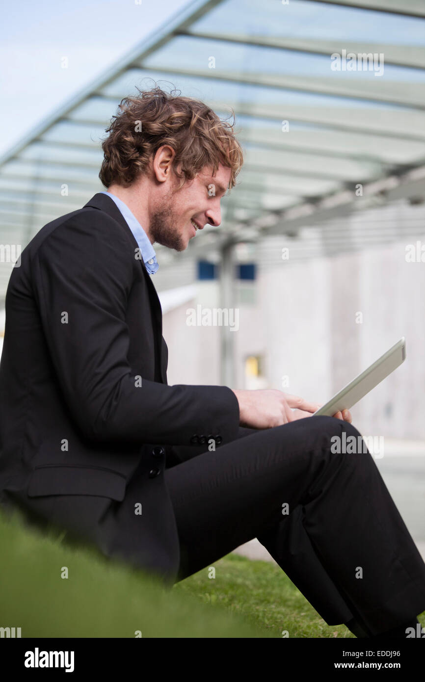 Geschäftsmann, sitzen auf einer Wiese mit seiner digital-Tablette Stockfoto