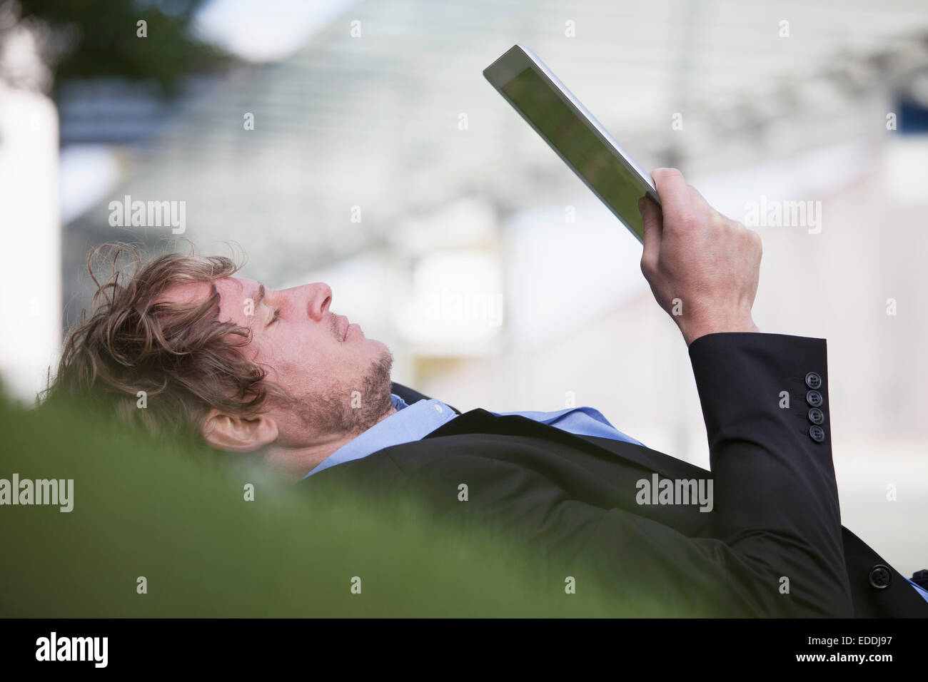 Geschäftsmann, liegend auf einer Wiese mit seiner digital-Tablette Stockfoto