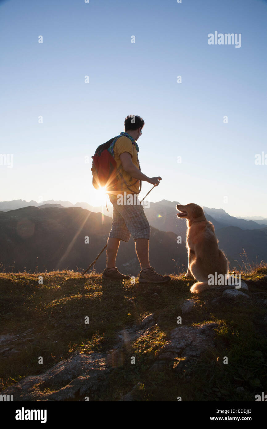 Österreich, Tirol, Unterberghorn, Wanderer mit Hund bei Sonnenaufgang Stockfoto