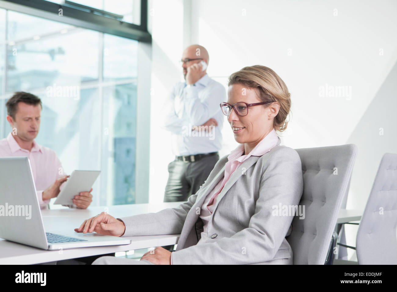 Drei Unternehmer mit Laptop, digitale Tablet und Handy im Konferenzraum Stockfoto