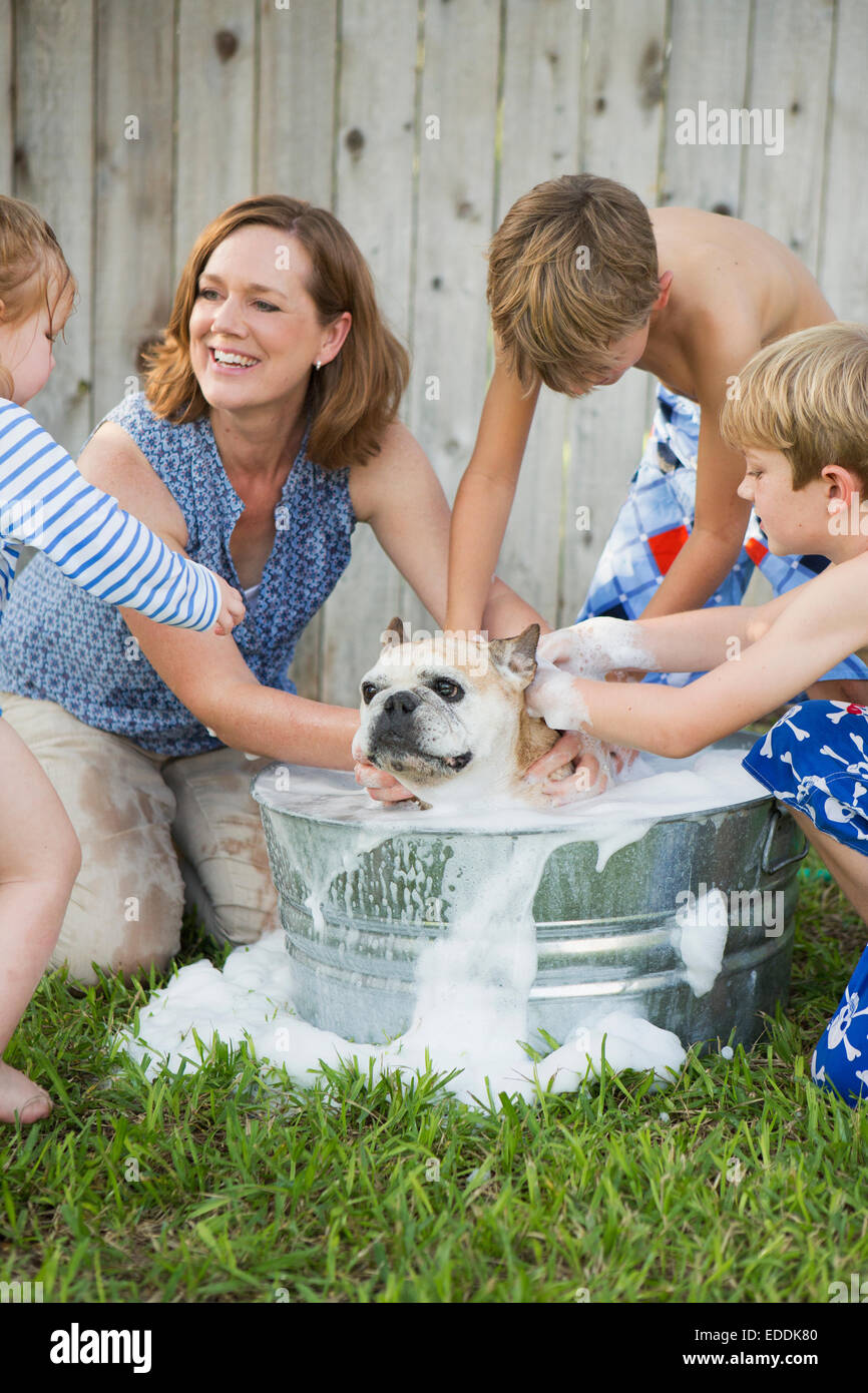 Eine Familie in ihrem Garten einen Hund in der Badewanne zu waschen. Stockfoto