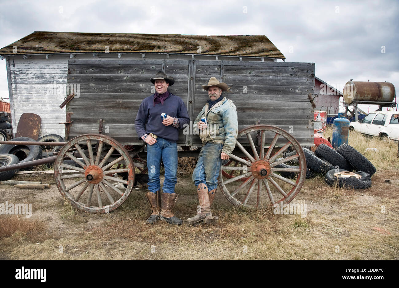 Zwei Männer in Cowboy-Hüte und Cowboy-Stiefel an einem Holzwagen gelehnt. Stockfoto