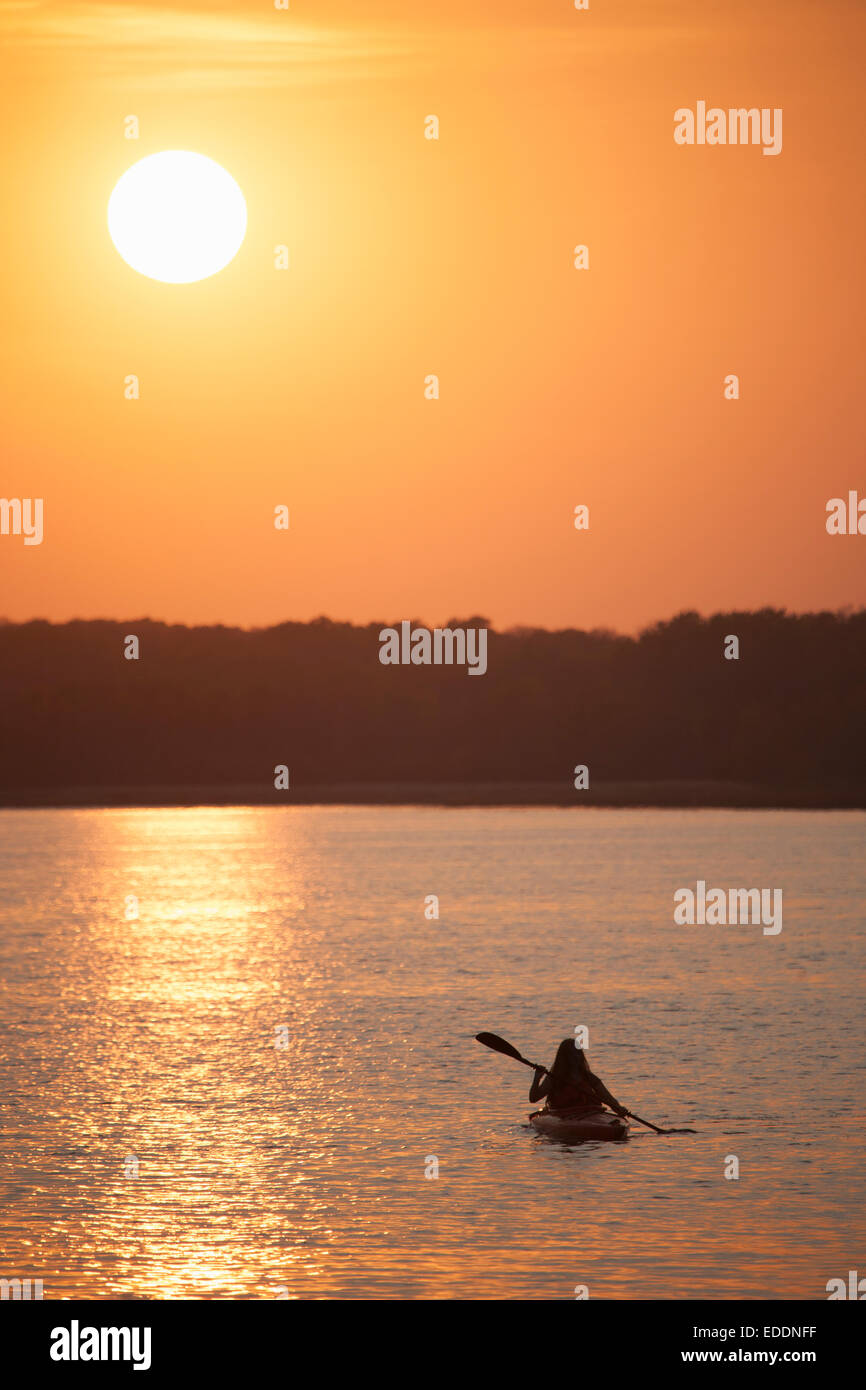 Kajakfahrer bei Sonnenuntergang auf einem ruhigen See. Stockfoto