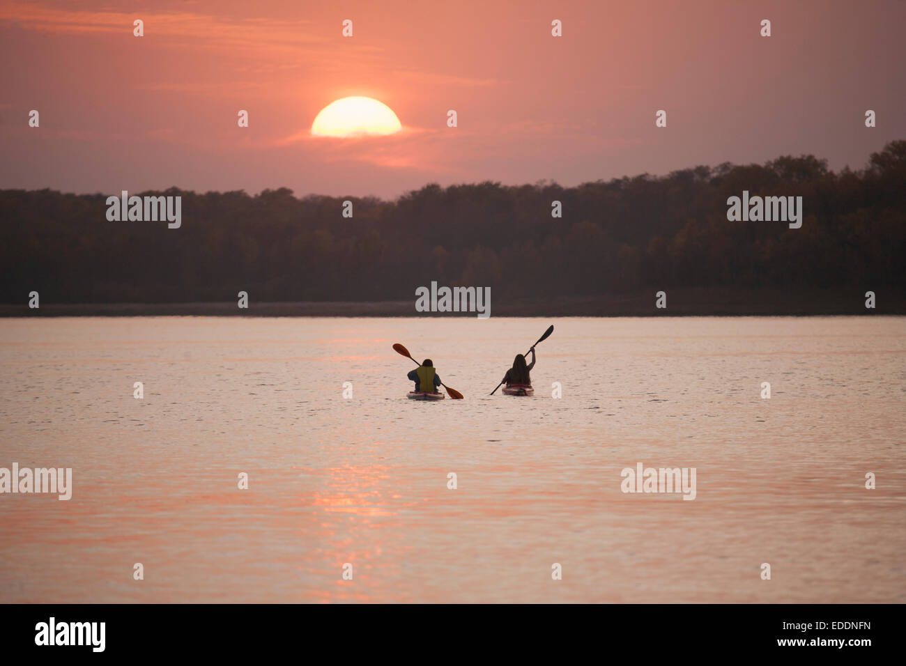 Zwei Kajakfahrer bei Sonnenuntergang auf einem ruhigen See. Stockfoto