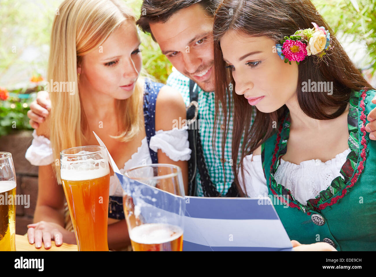 Freunde, die zusammen betrachten Getränkekarte Biergarten in Bayern Stockfoto