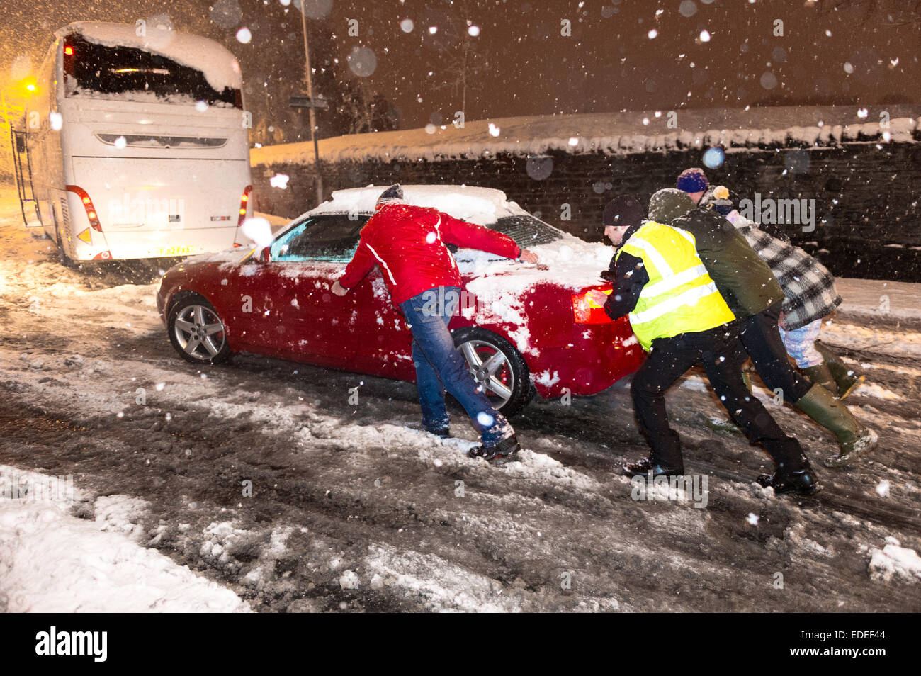 Eine Gruppe von Männern helfen, ein Auto vorbei an einen gestrandeten Trainer während eines Schneesturms in Mansfield Woodhouse Nottinghamshire schieben. Stockfoto