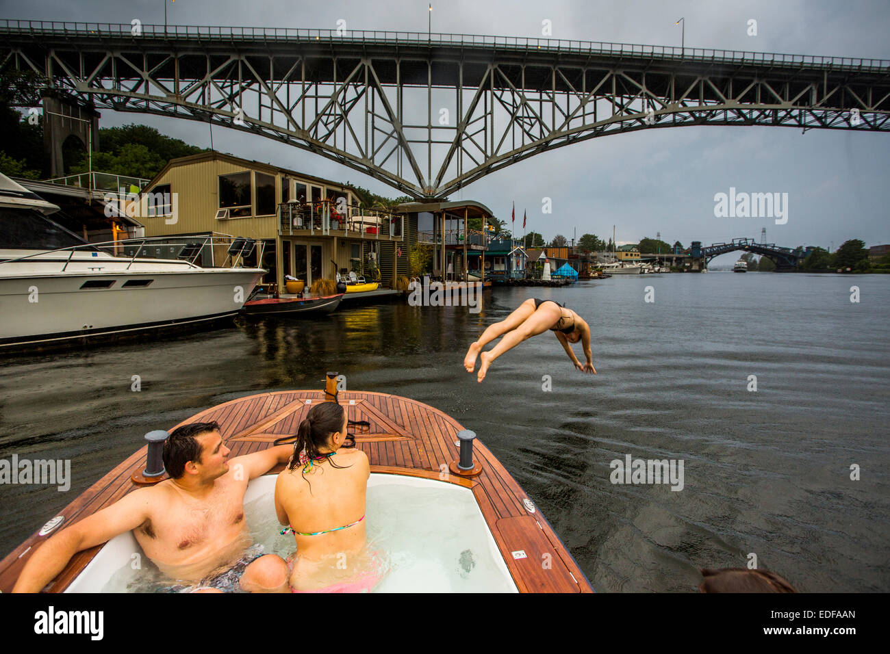 Eine junge Frau taucht aus dem Bug eines Bootes Whirlpool in Lake Union während ein Sturm. Stockfoto