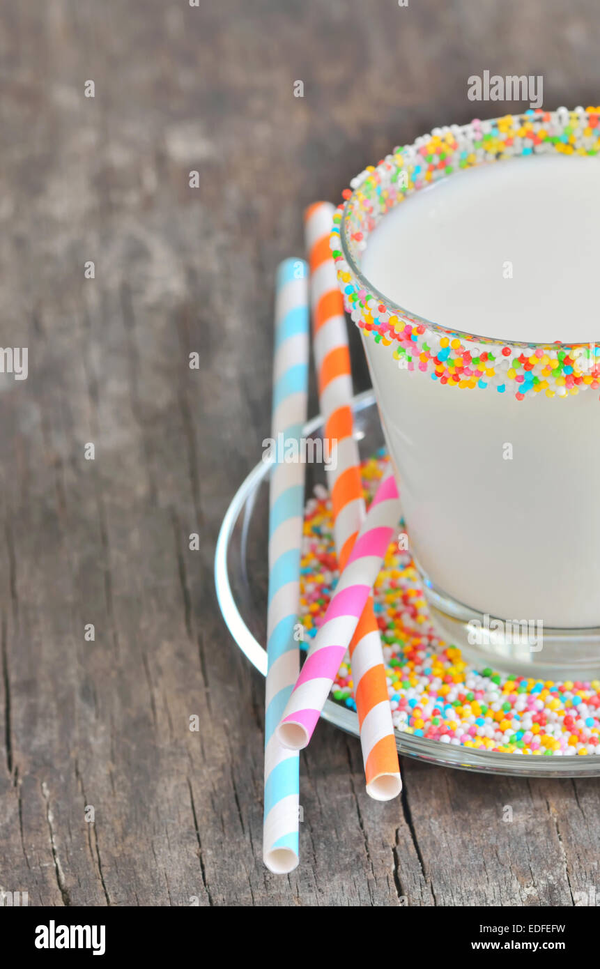 Glas Milch mit gestreiften Strohhalme auf alten hölzernen Hintergrund Stockfoto