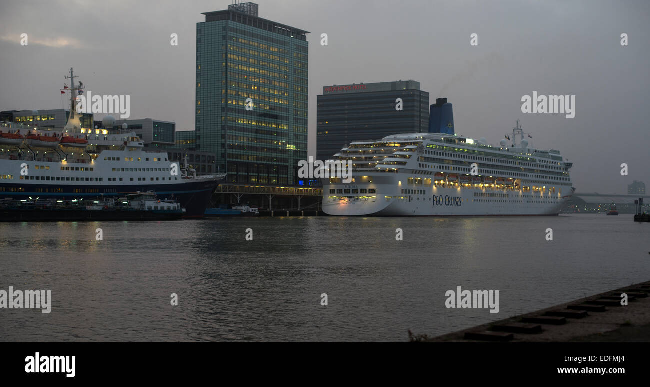 Zwei Kreuzfahrtschiffe vor Anker am Terminal Amsterdam Passagiere in der Abenddämmerung mit Skyline der Stadt im Hintergrund Stockfoto