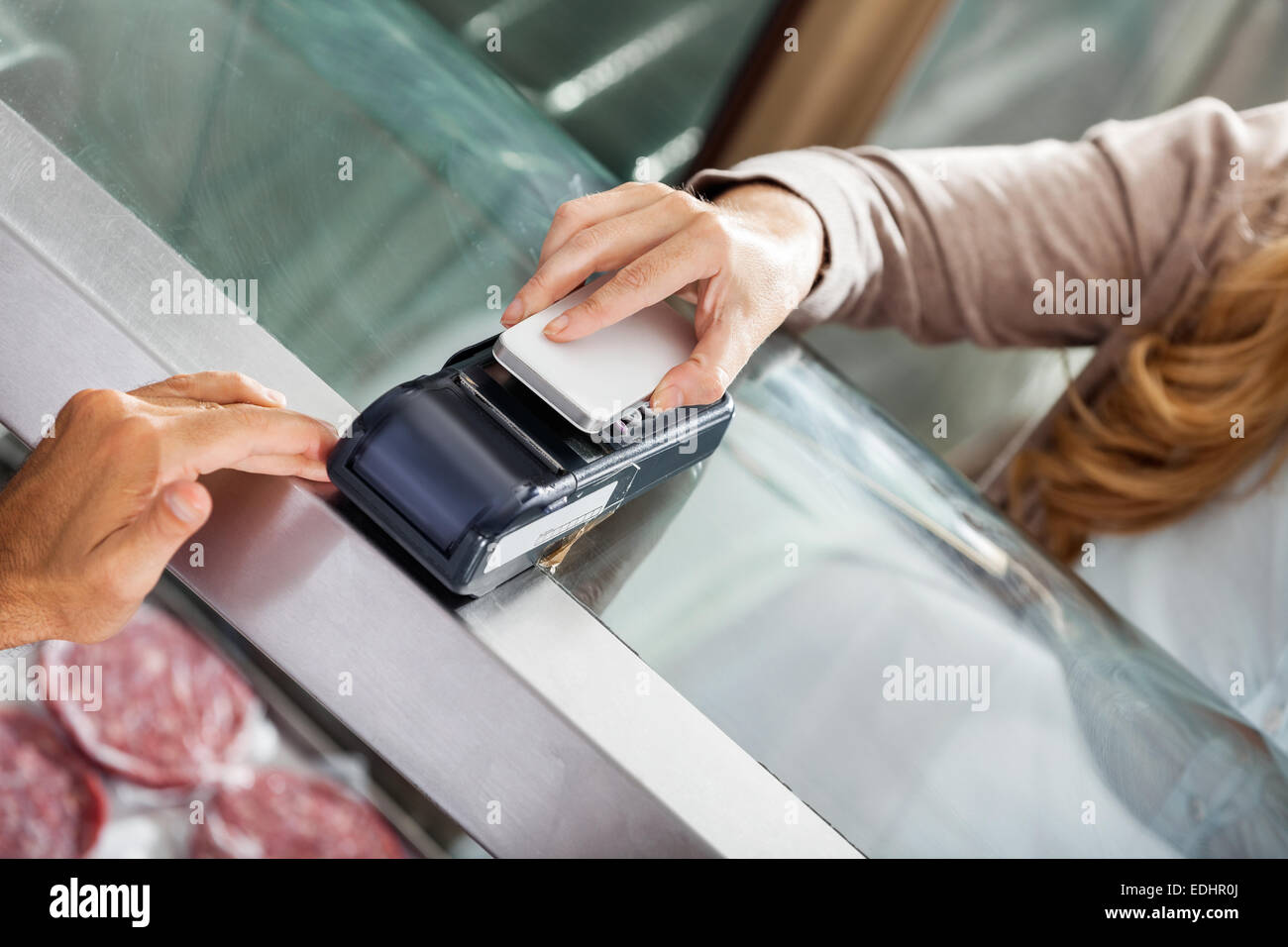 Kunden die Zahlung durch Smartphone in Metzgerei Stockfoto