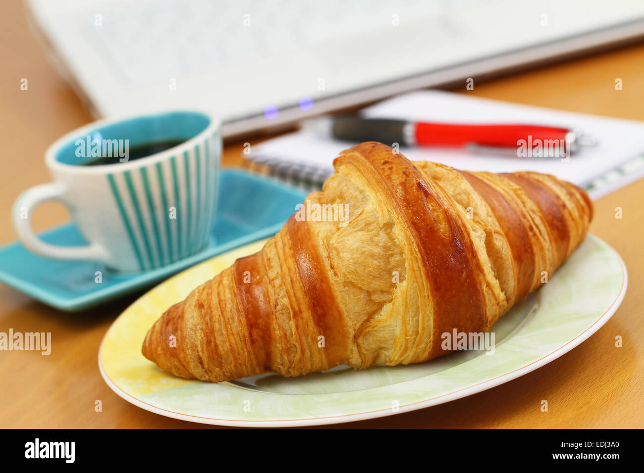 Croissant und Kaffee am Schreibtisch Stockfoto