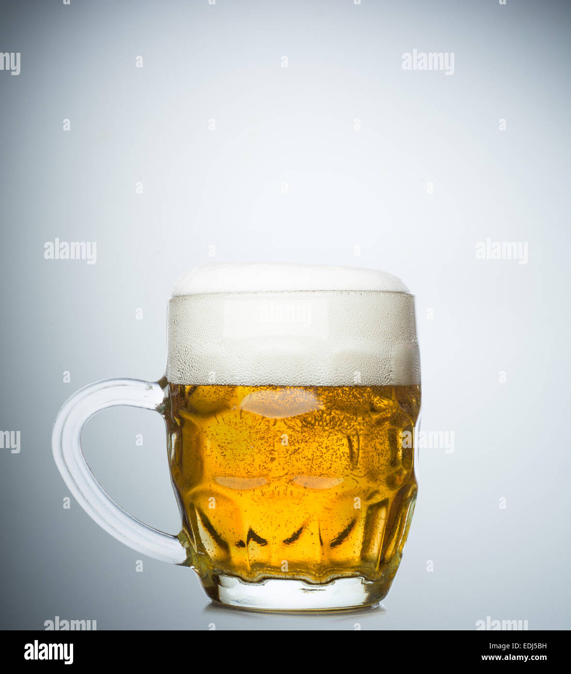 Becher mit frischem Bier und Kappe des Schaums auf weißem Hintergrund Stockfoto