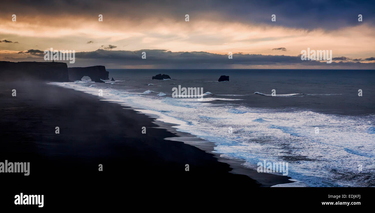 Wellen am Ufer mit Dryholaey im Hintergrund, Island. Dyrhólaey übersetzt bedeutet "Der Tür Loch Island" Stockfoto