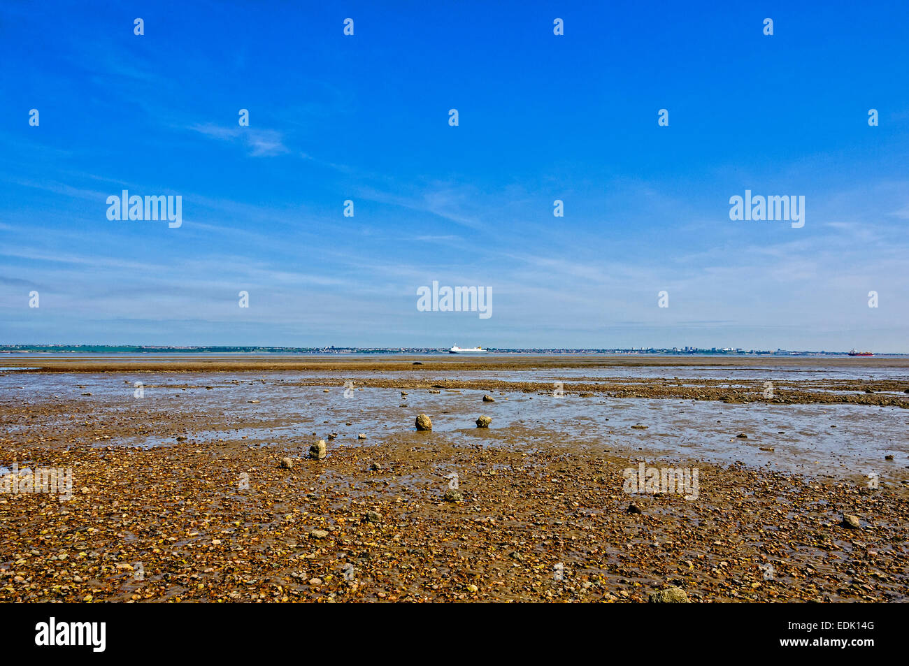 Zwei Schiffe in entgegengesetzte Richtungen auf einem ruhigen Themse vorbei an einem schlammigen Kiesstrand unter einer intensiven blauen Himmel Stockfoto