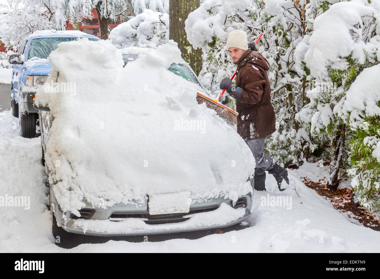 Ein Mann reinigt ein Auto von Schnee mit einem Besen Stockfotografie - Alamy