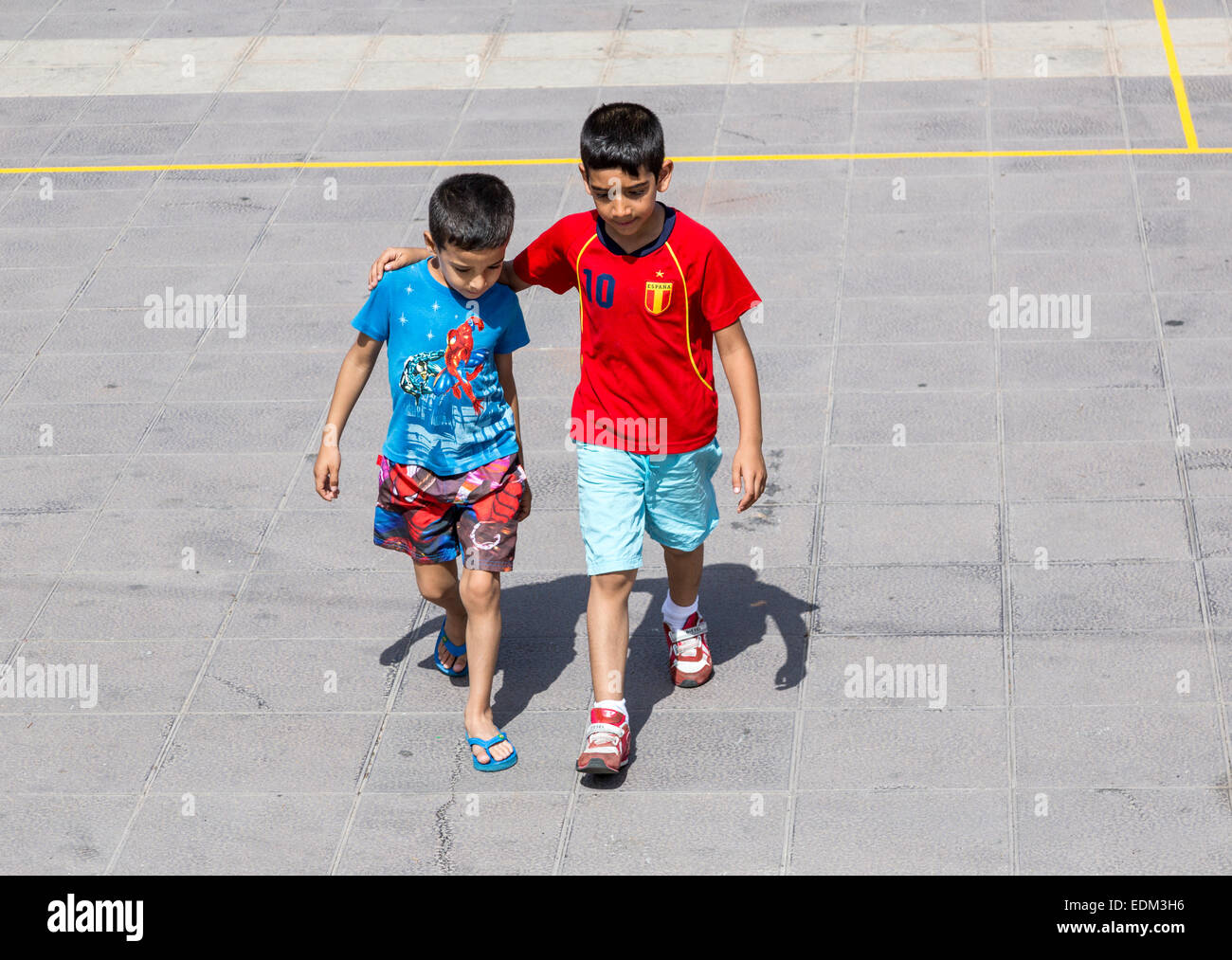 Jungen, die zu Fuß über die gepflasterte Fläche mit Arm um die Schultern, Teguise, Lanzarote, Kanarische Inseln, Spanien Stockfoto