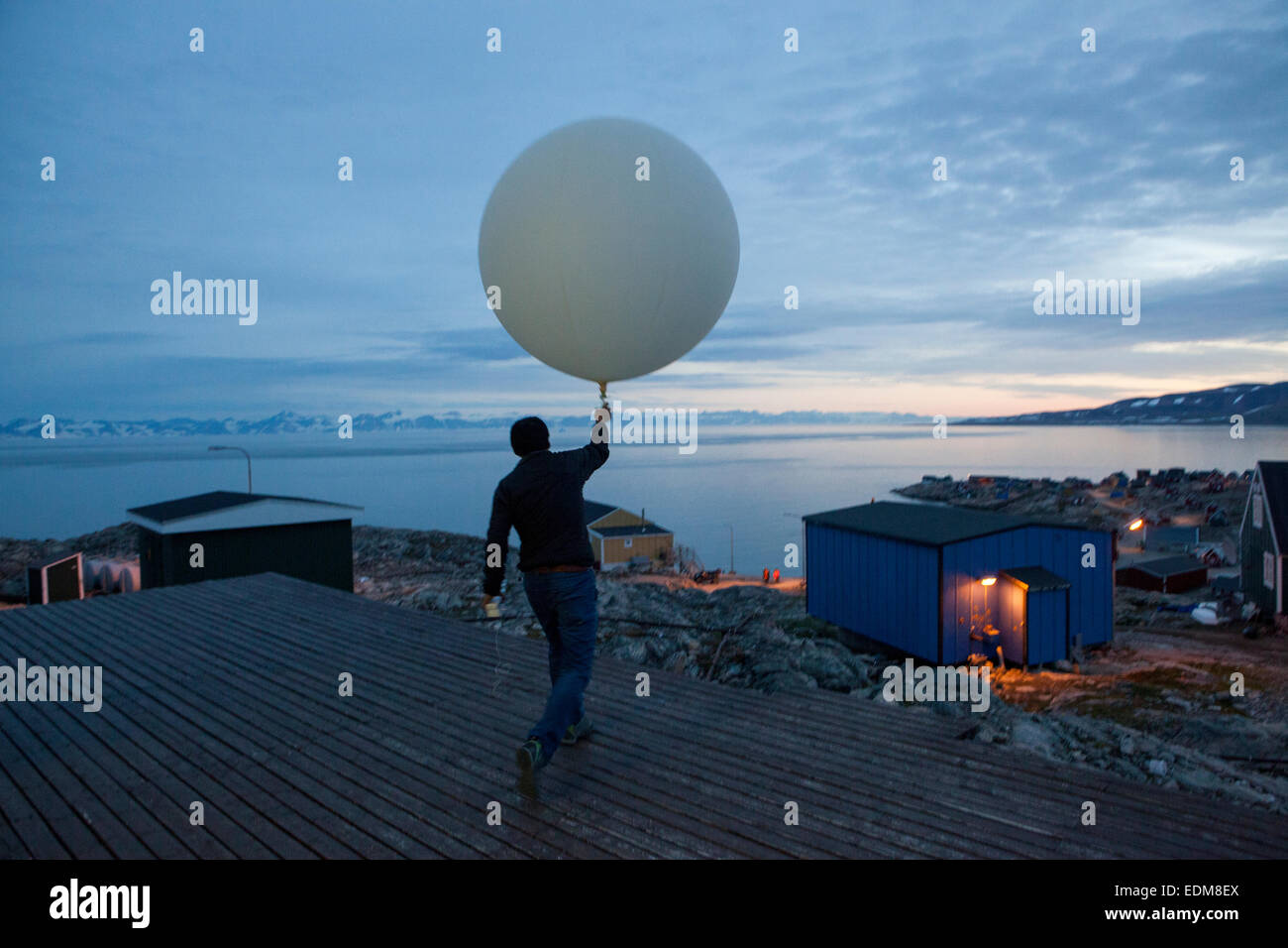 Mann loslassen einen Wetterballon über Ittoqqortoormiit, Scoresby Sund, Ostgrönland. Stockfoto