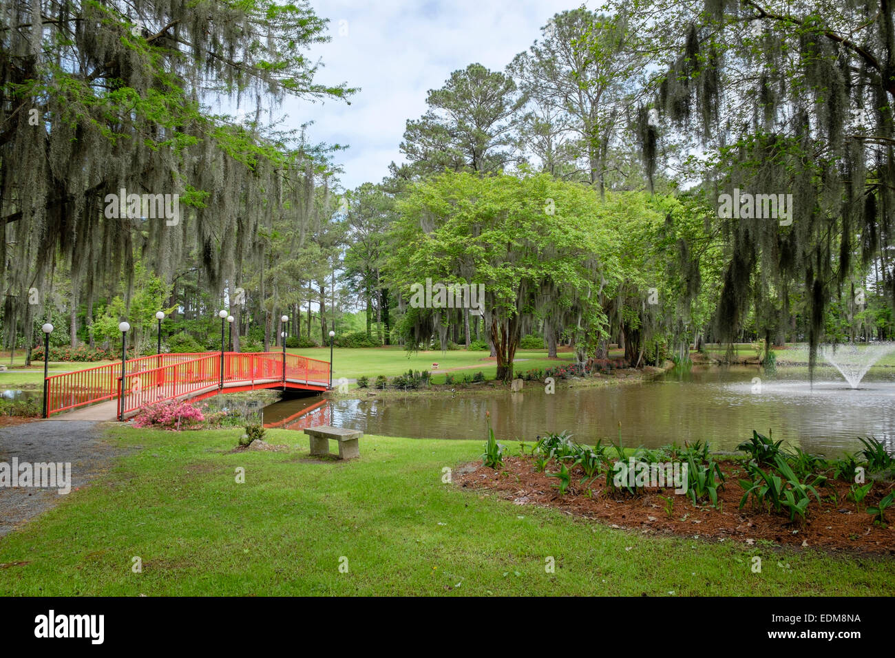 Ruhige caffco's Blumen outlet Garten mit See und rote Fußgängerbrücke in wetumpka Alabama, USA. Stockfoto