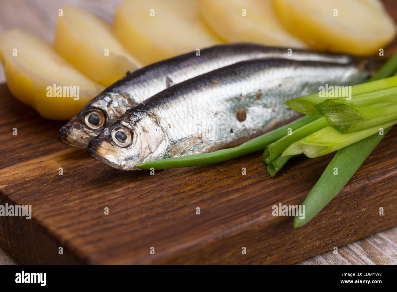 würzige gesalzene Sardellen, Zwiebeln und Kartoffeln auf einem Holzbrett Stockfoto