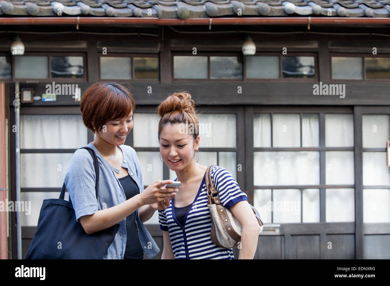 Zwei Frauen stehen im Freien, mit Blick auf Handy. Stockfoto