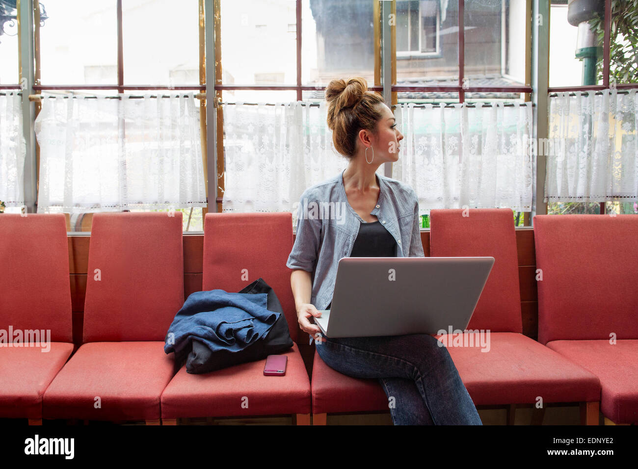 Eine Frau auf einem Laptop arbeiten und drinnen sitzen. Stockfoto