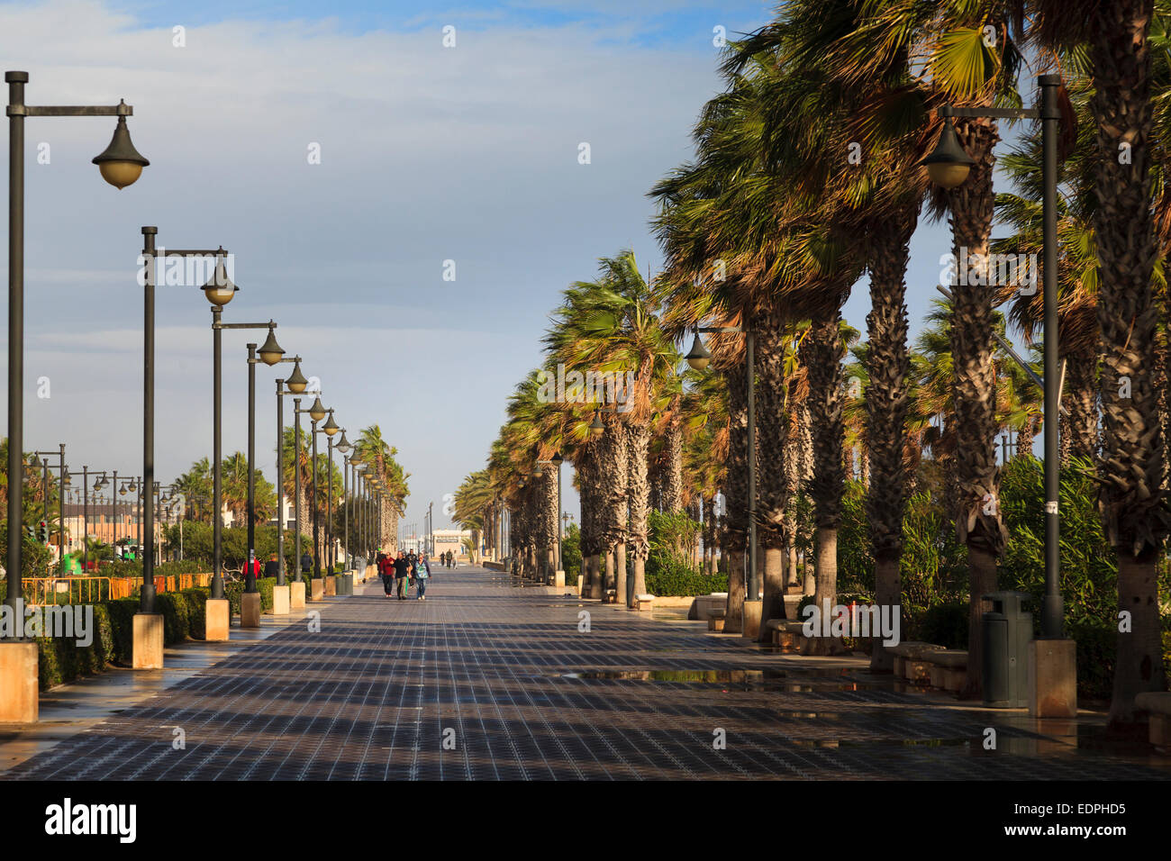 Ein paar Leute zu Fuß entlang der Promenade von Valencia Strand mit windigen Palmen und Wintersonne Stockfoto
