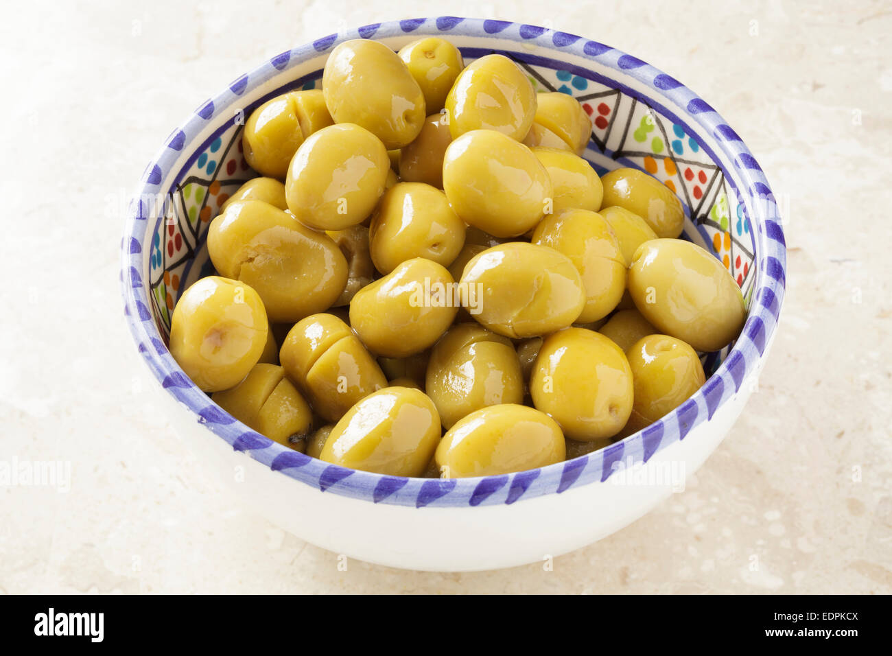 Grüne Oliven in eine Schüssel geben. Stockfoto