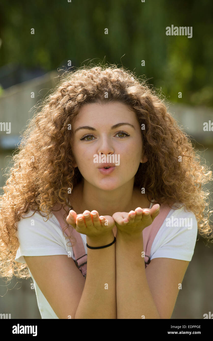 Attraktive Teenagerin weht einen Kuss in der Handfläche von ihrer hand Stockfoto