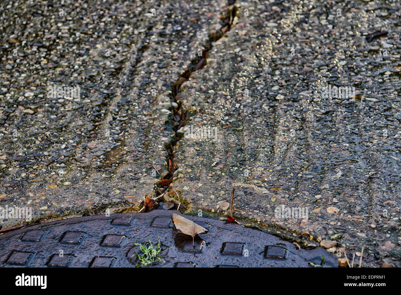 Gerissenen Beton Antrieb mit Metall Abfluss Inspektion Platte Stockfoto