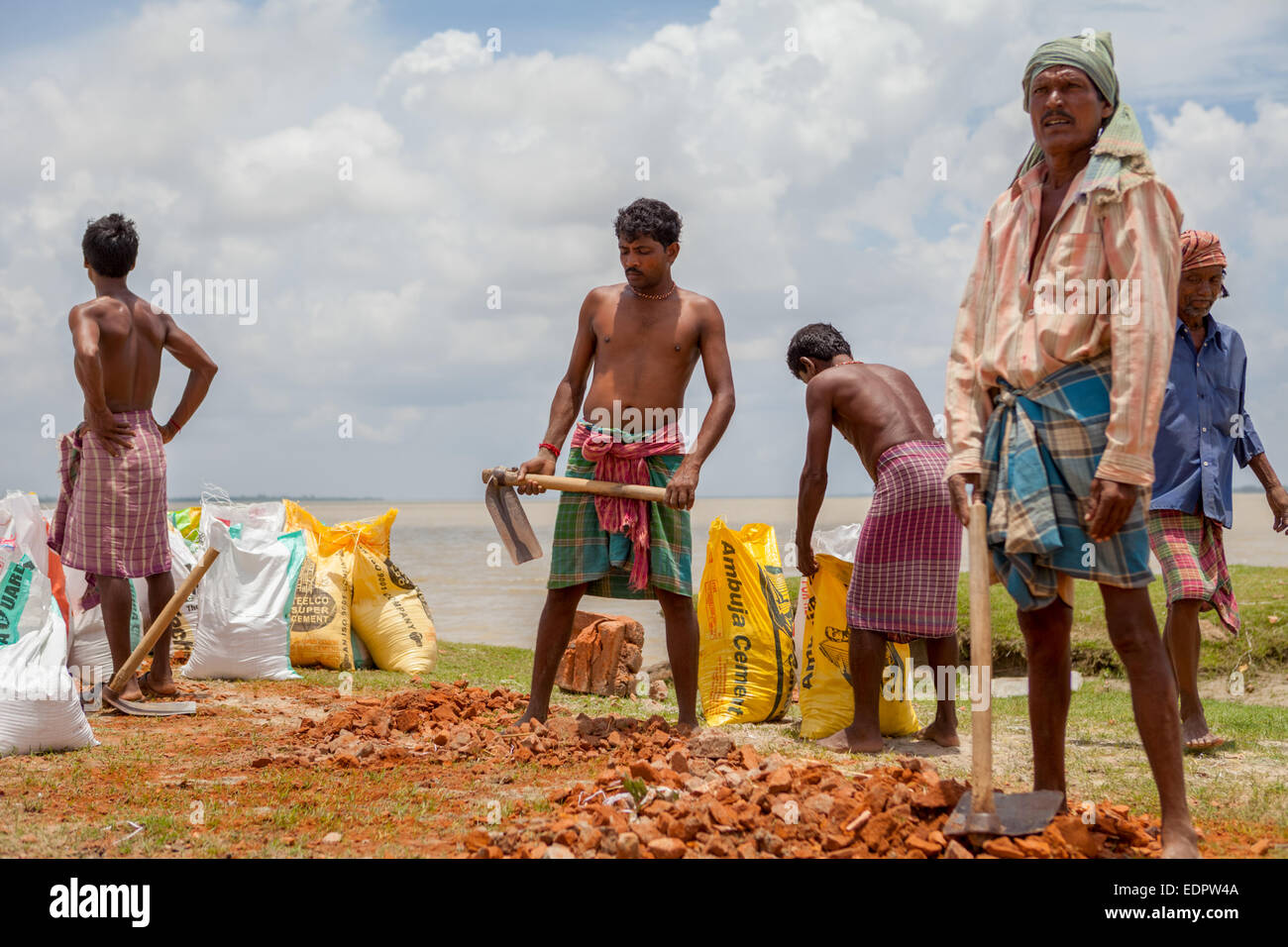 Arbeiter, die Säcke mit Ziegelsteinen für das Projekt zur Kontrolle der Flusserosion am Ufer des Ruppnarayan-Flusses in Tamluk, Westbengalen, Indien, füllen. Stockfoto