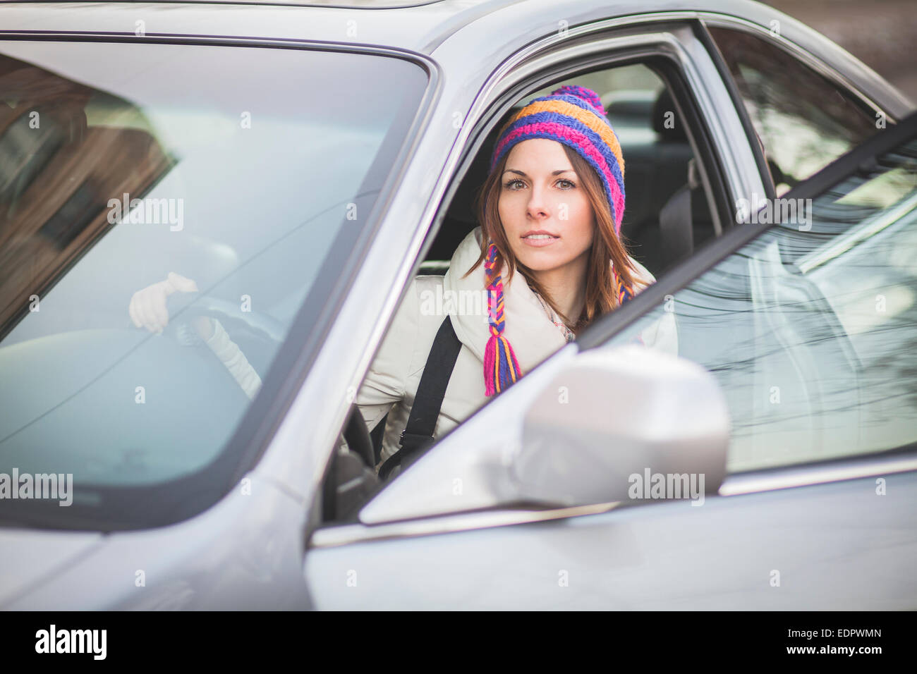 Positive Mädchen sitzt in einem geparkten Auto in der Nähe von der Autovermietung Stockfoto