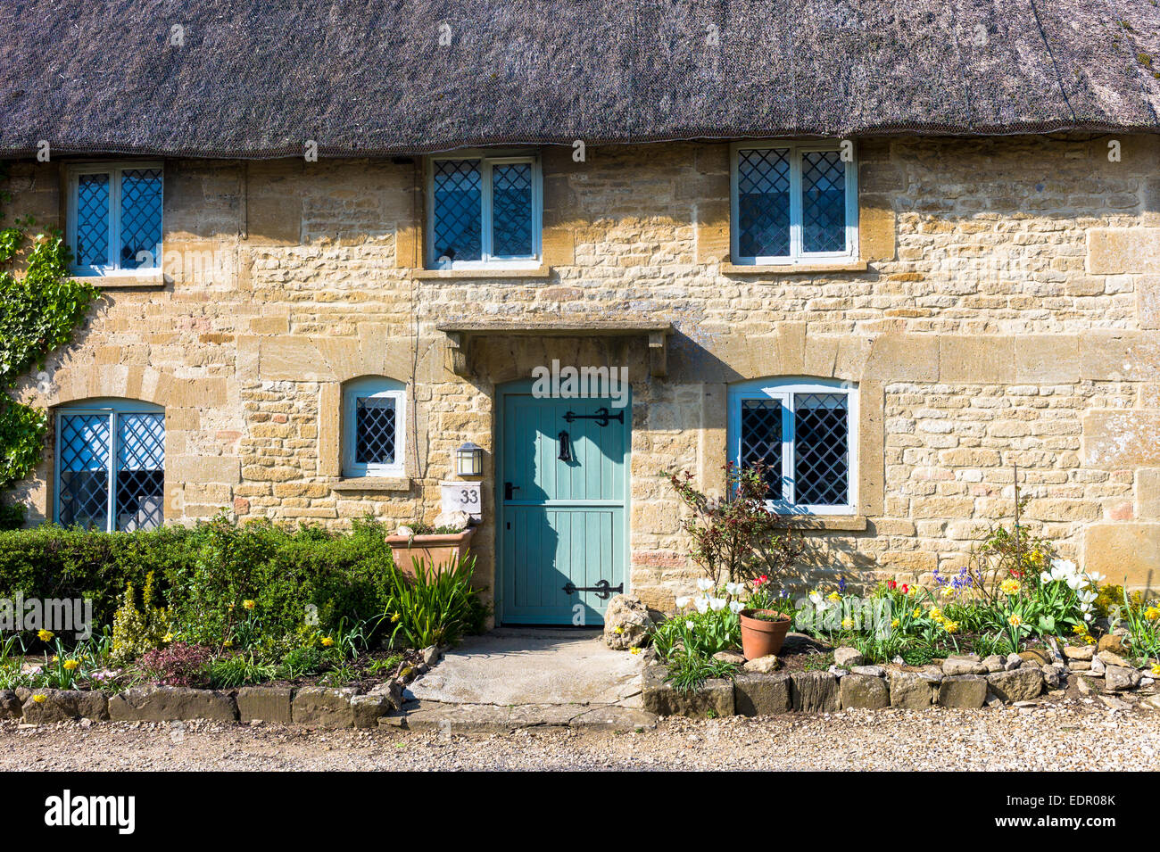 Idyllischen reetgedeckten Häuschen mit traditionellen thatching und hellen Bleiglasfenster am Taynton in Cotswolds, Oxfordshire, Vereinigtes Königreich Stockfoto