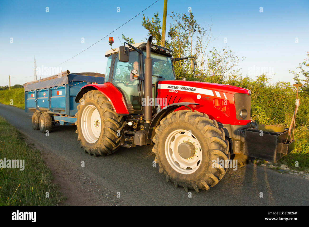 Traktor fahren entlang Landstraße in Suffolk, UK Stockfoto