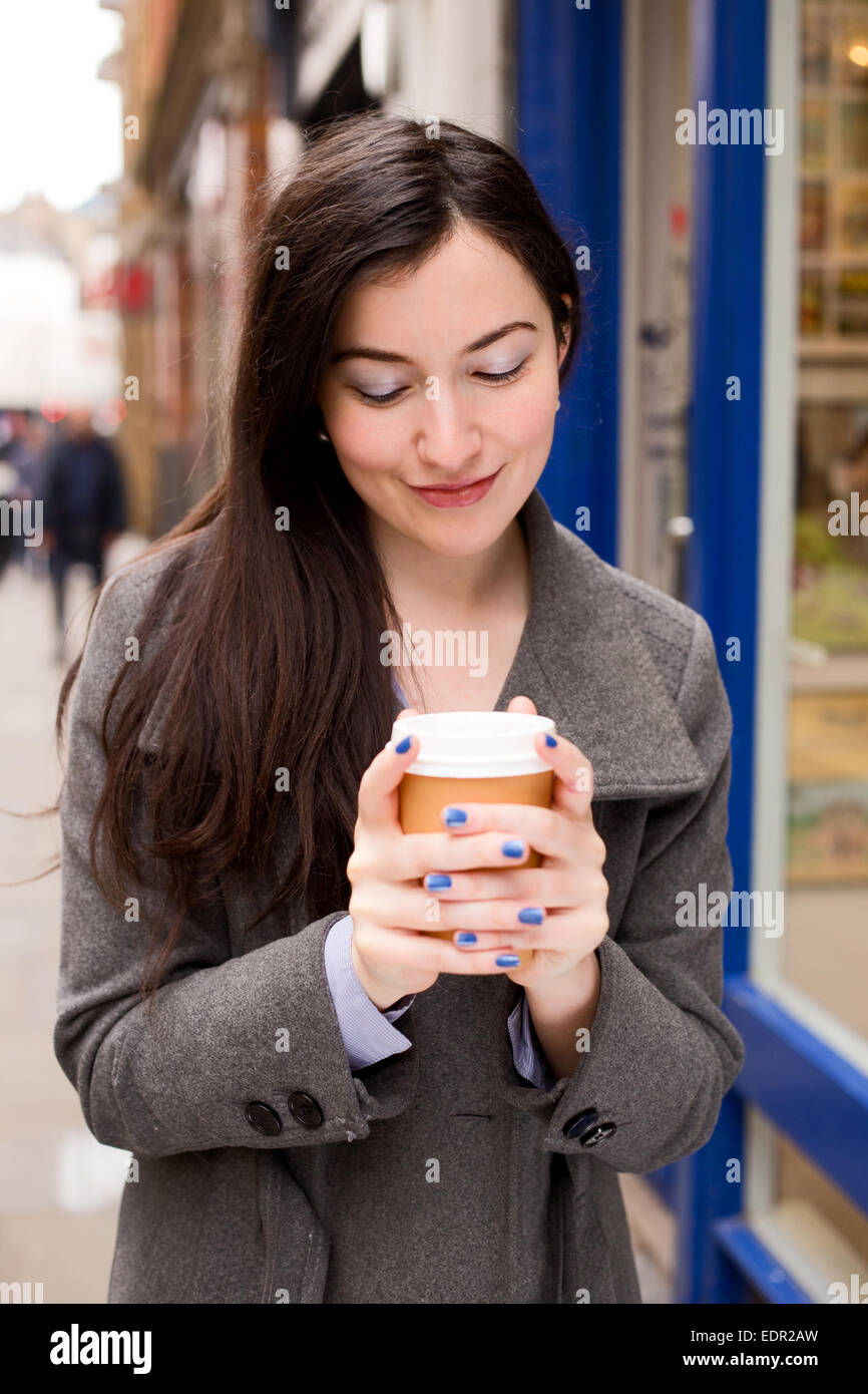 junge Frau hält einen Kaffee auf der Straße Stockfoto