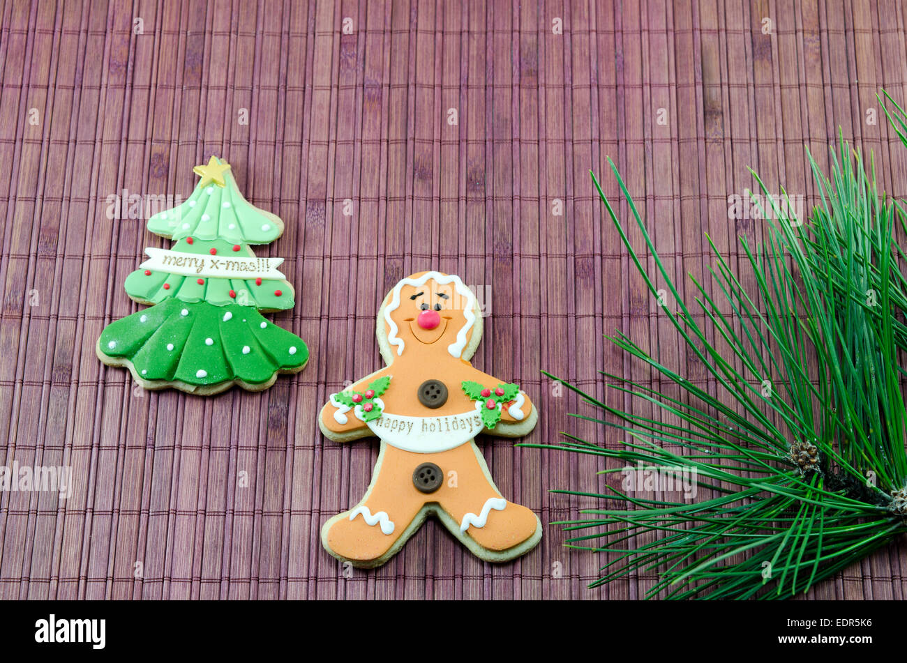 Essbare Lebkuchen und ein Weihnachtsbaum dekoriert mit Tannennadeln auf einem Bambus-Oberfläche Stockfoto