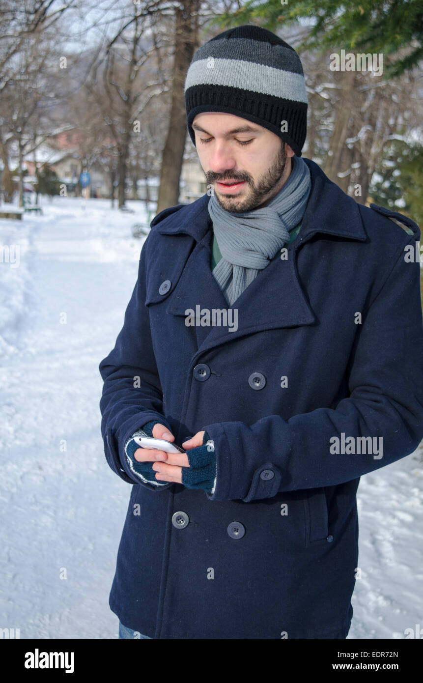 Junge Lumbersexual Mann SMS im kalten winter Stockfoto