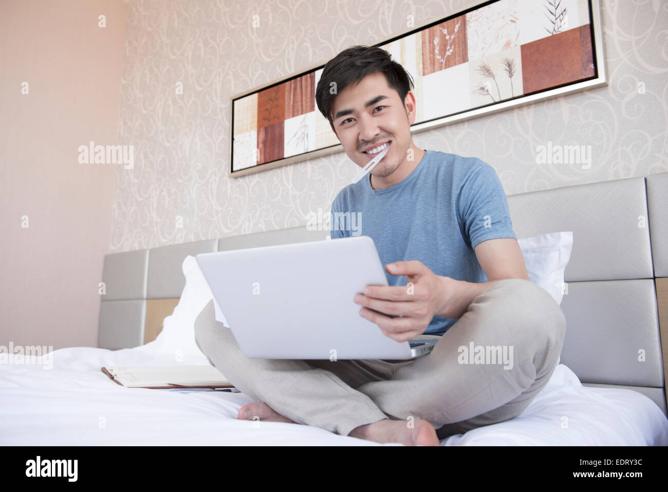 Junger Mann im Bett, Zähneputzen mit laptop Stockfoto