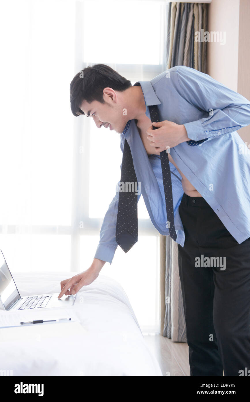 Junger Mann beim anziehen, während mit laptop Stockfoto