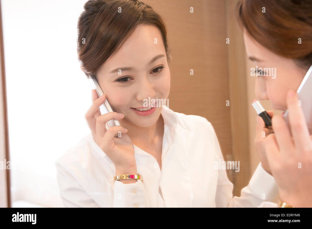 Junge Frau über die mobile Umsetzung auf Lippenstift Stockfoto
