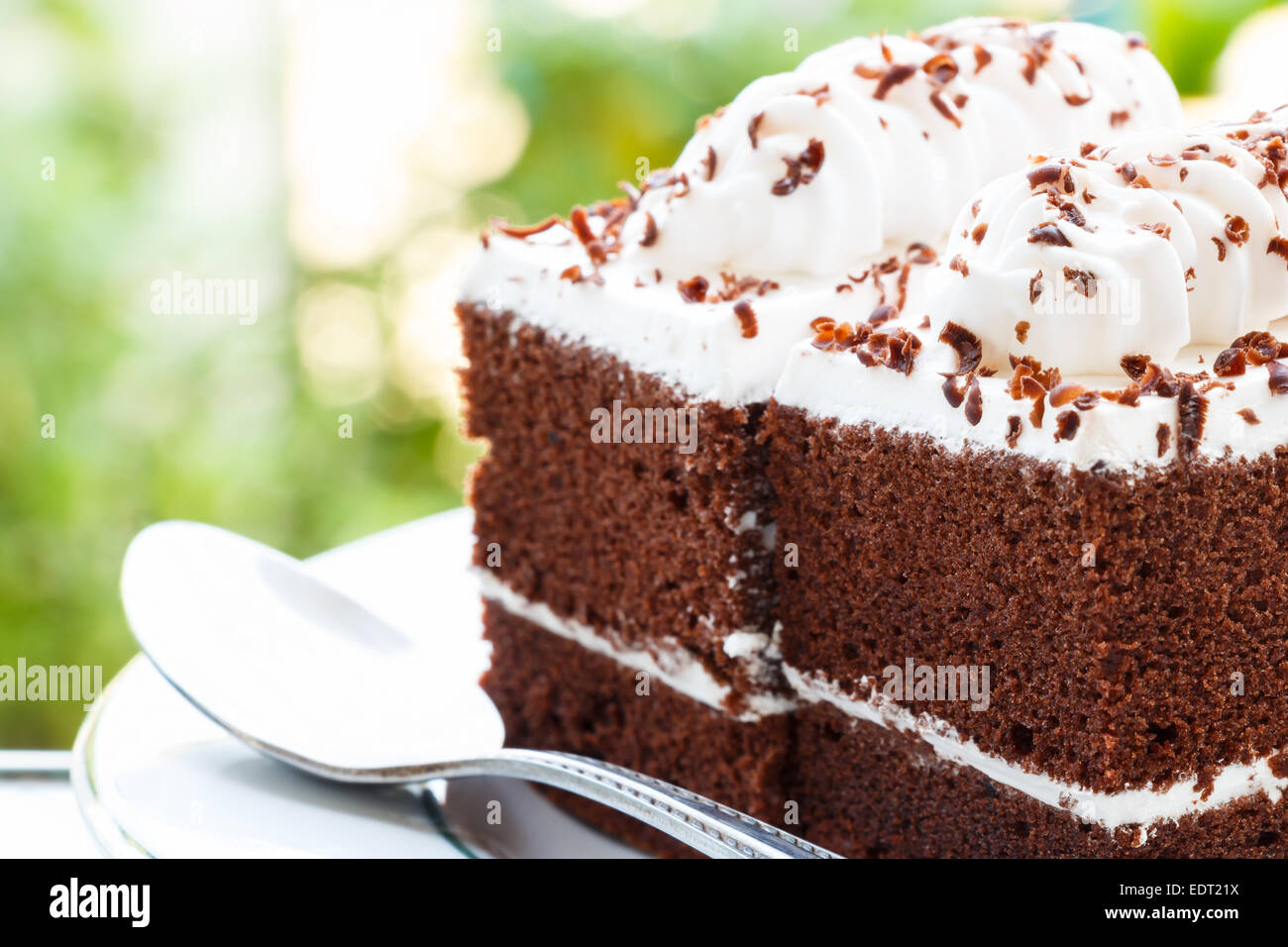 Nahaufnahme von Schokolade Kuchen mit weißen Creme auf der Oberseite und Bokeh im Hintergrund Stockfoto