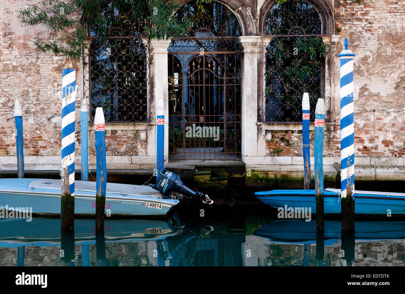 Boot vor Anker, blau + weiß Beiträge auf einem Kanal in Venedig Stockfoto