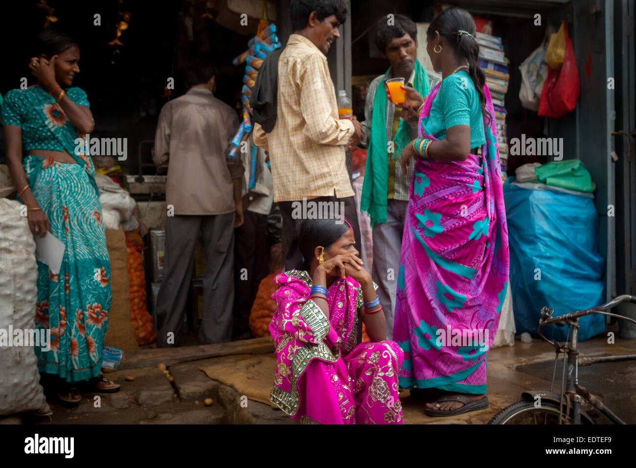 Personen, die sitzen und stehen, während andere Kunden ein Gruppengespräch vor einem allgemeinen Geschäft in Rajgir, Bihar, Indien, führen. Stockfoto