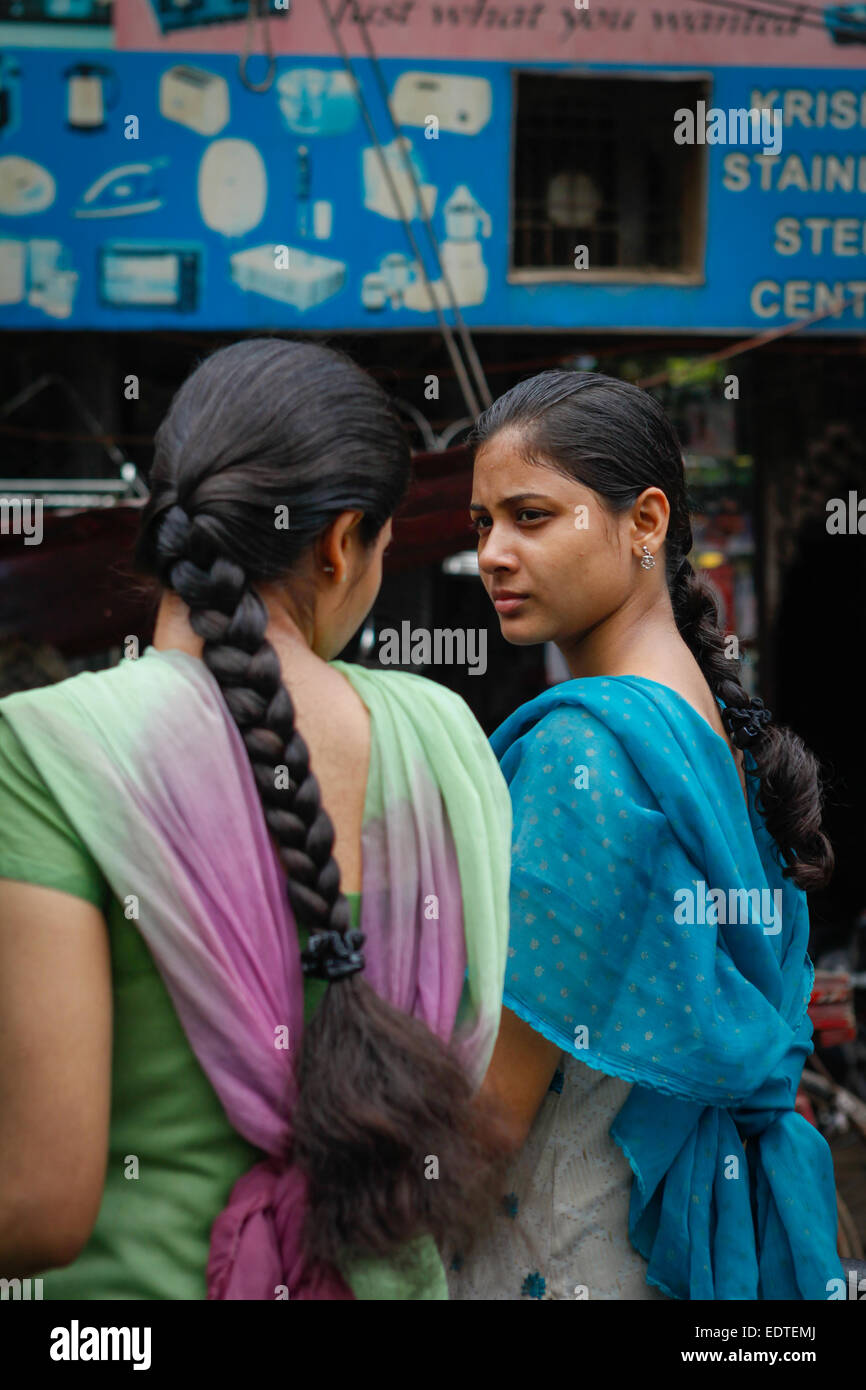 Mädchen, die während eines Verkehrsstaus ein Gespräch führen, während sie in Varanasi, Uttar Pradesh, Indien, Fahrrad fahren Stockfoto