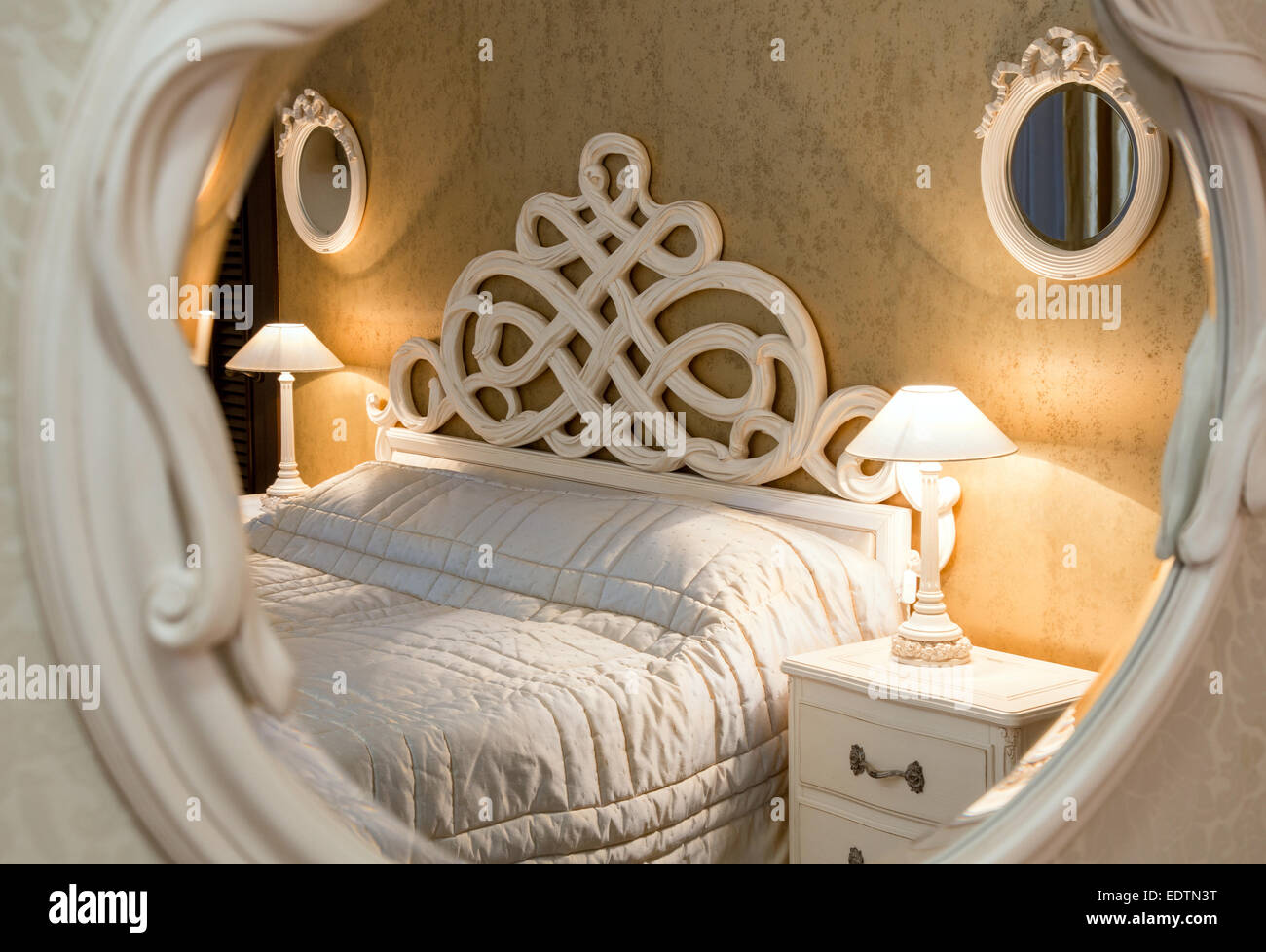Weiße Vintage-Stil geschnitzten Bett und Nachttisch mit Lampen Sen durch den geschnitzten Spiegel Stockfoto