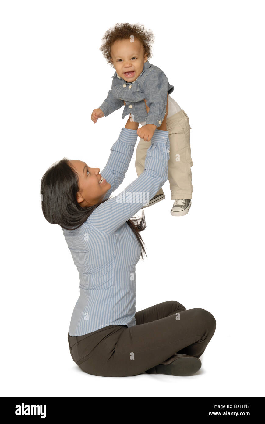 Attraktive junge Mutter sitzt und hält ihre lächelnden einjährigen Sohn. Stockfoto