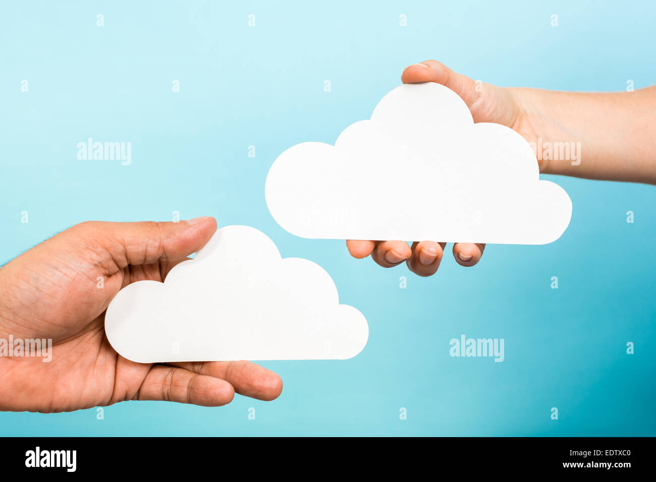 Zwei Hände halten Papier Wolken auf blauem Hintergrund. Cloud-computing-Konzept. Stockfoto