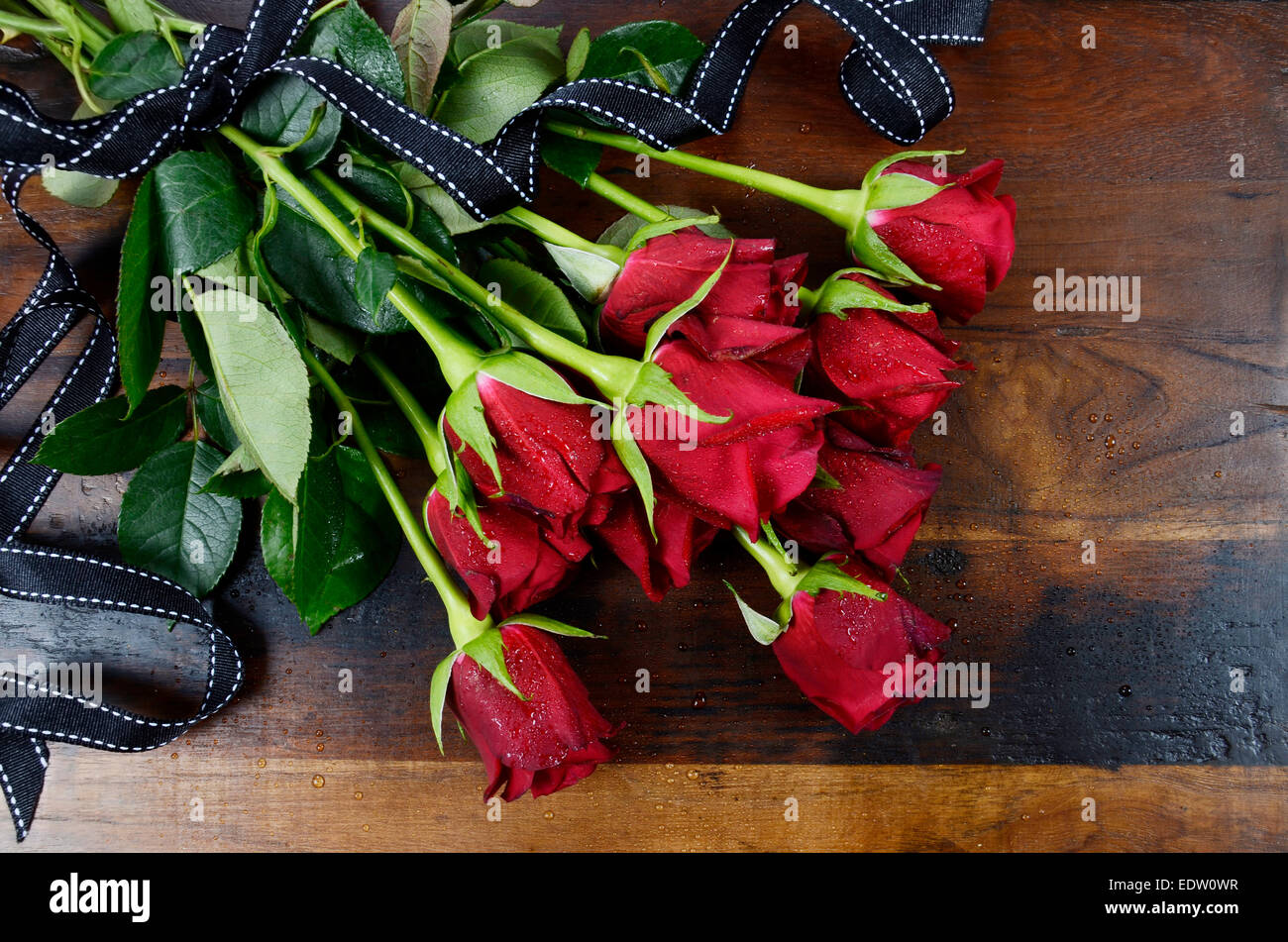 Happy Valentinstag rote Rosen auf dunkle recycelt Holz Hintergrund - overhead mit schwarzen Band. Stockfoto